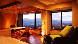 Une chambre à coucher comprenant un lit, un bureau, une chaise et offrant une vue sur les montagnes grâce à de grandes fenêtres.