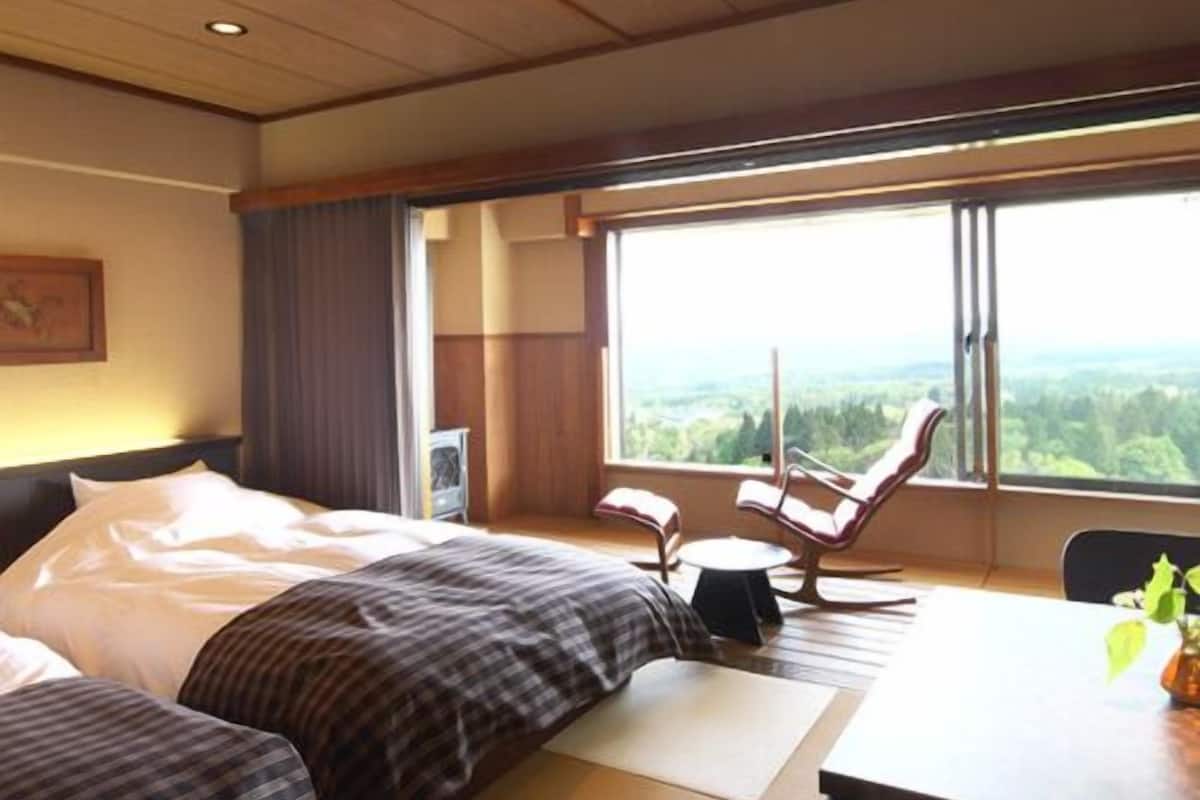 Une chambre d’hôtel avec un lit, un bureau, une chaise et une vue sur le paysage.