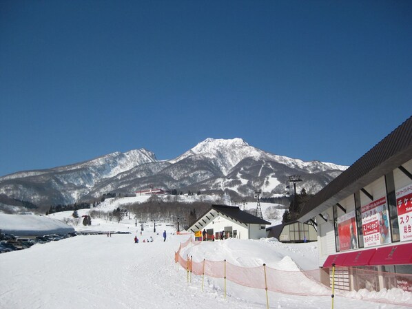 A ski resort with a mountain backdrop, a ski lift, and a building with signage.
