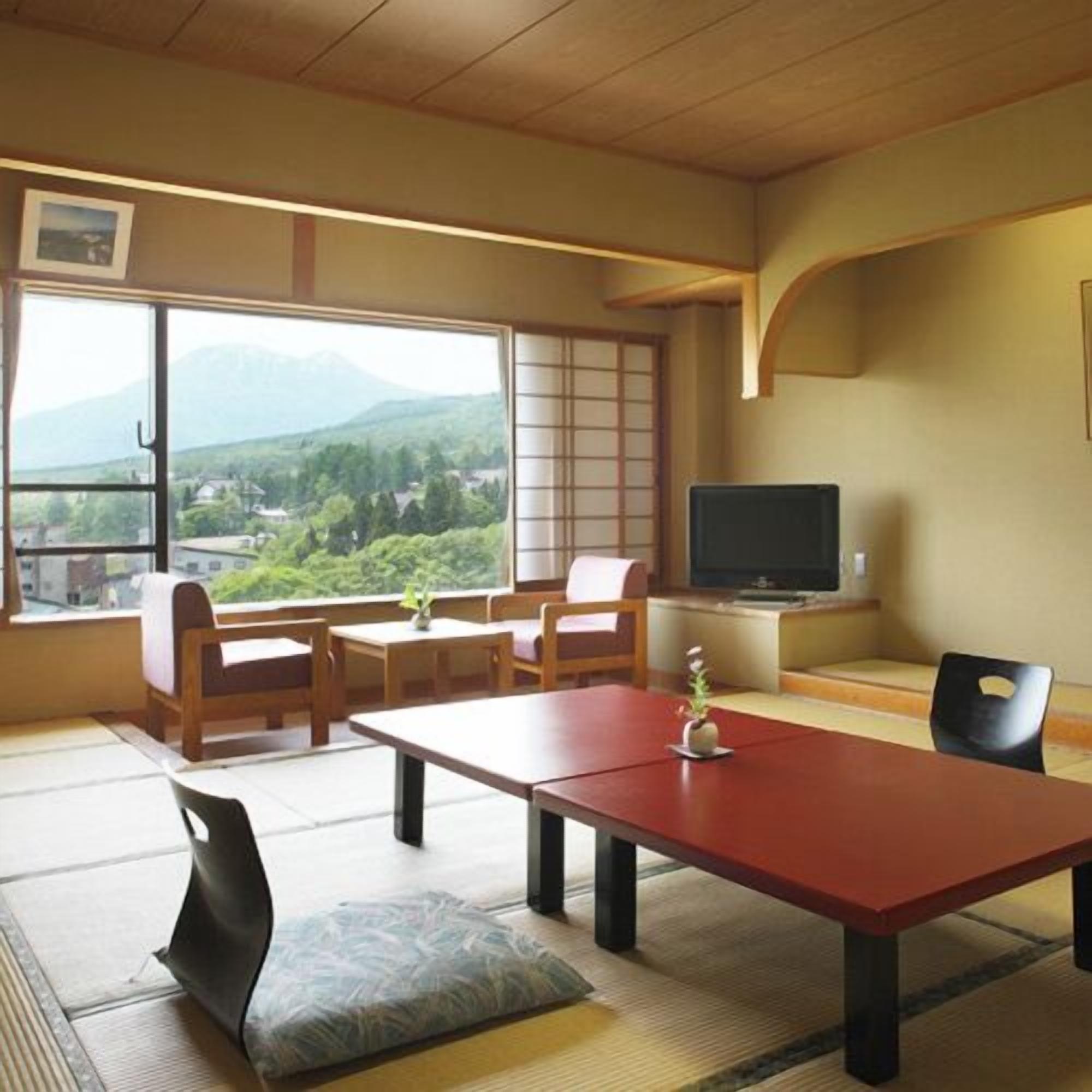 A traditional Japanese-style room with tatami flooring, a low table, and a television on a stand.