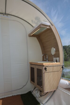 A compact, circular room with a wooden counter, a sink, and a mirror.