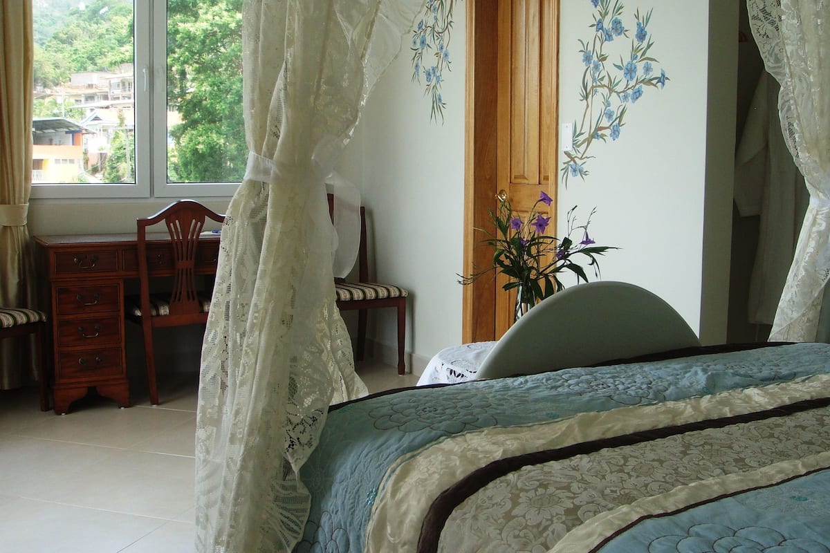 A bedroom with a bed, a wooden desk, and a chair.