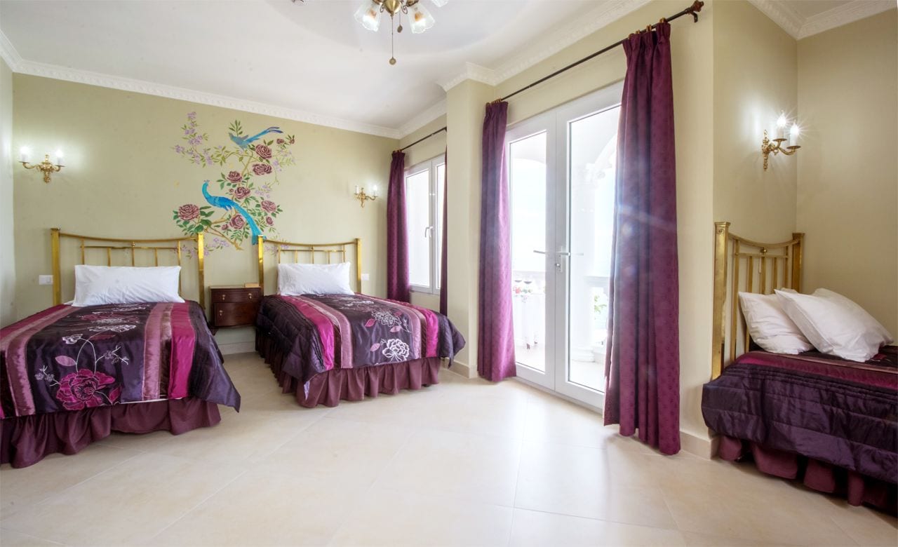 A room with two beds, a mural, and a balcony.