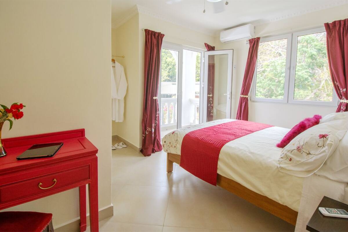 A bedroom with a bed, a desk, and a window.
