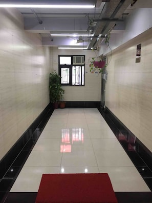 A spacious hallway with a red carpet, tiled floors, and a window with an air conditioning unit. - Park Inn (Kowloon)