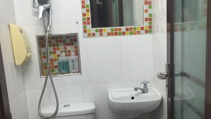 Un baño pequeño con inodoro, lavamanos y ducha.