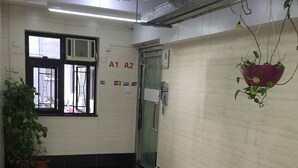 Un pasillo limpio y bien iluminado, con suelo de baldosas, una puerta de cristal con manija y un ventilador de techo.