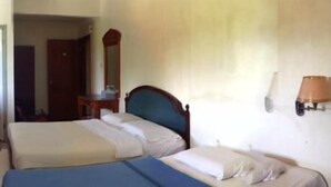 Ein Hotelzimmer mit zwei Betten, einem Fernseher, einem Schreibtisch und einem Spiegel.
