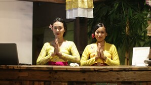 Two individuals at a reception desk with a laptop and a notepad. - Green Bird Villa (Ubud)