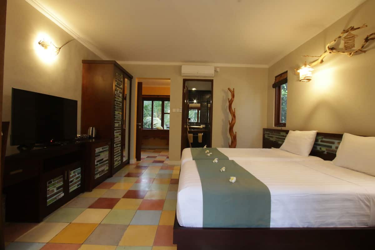 A hotel room with a large bed, a television, a minibar, and a view of the outdoors.