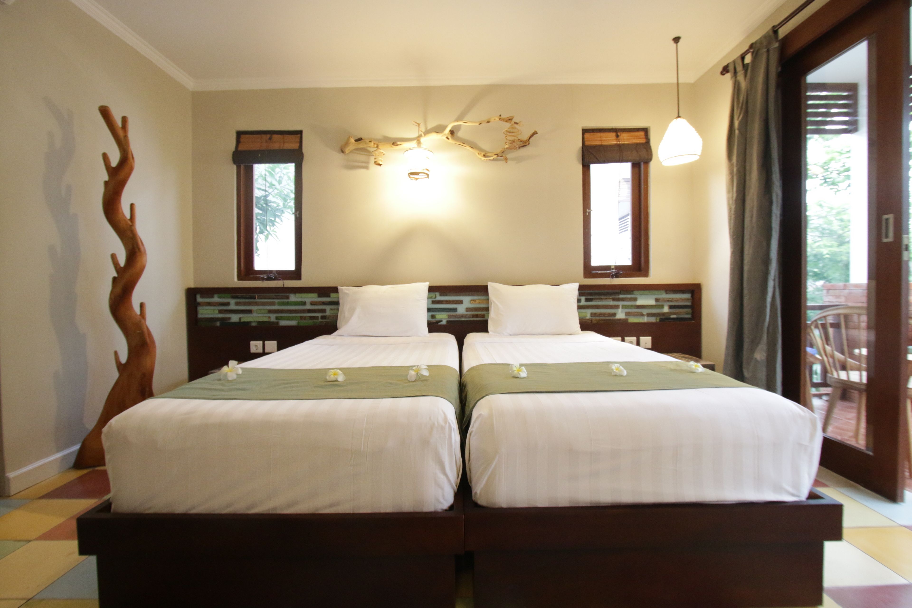 A double bed with a wooden headboard, a decorative wall piece, and a window with a view.