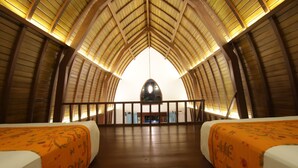 A high-ceilinged room with two beds, wooden flooring, and a central light fixture. - Green Bird Villa (Ubud)