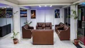 A modern living room with brown leather sofas, a coffee table, and potted plants. - Hotel Shivam Plaza (Kathmandu)