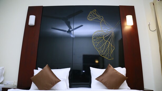 A hotel room with a bed, a ceiling fan, and a wall-mounted light fixture. - Sea port hotel (Negombo)