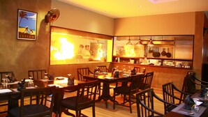 A restaurant with wooden tables and chairs, a ceiling fan, and a wall-mounted poster. - Sea port hotel (Negombo)