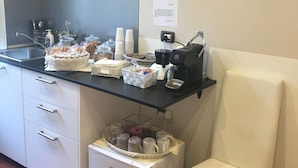 A kitchen area with a coffee machine, a basket of cookies, and a small refrigerator. - Relais Vatican Suites (Rome)