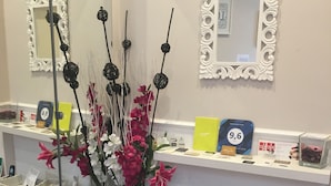 A reception area with a mirror, a vase of flowers, a counter with a phone, and a display of awards. - Relais Vatican Suites (Rome)