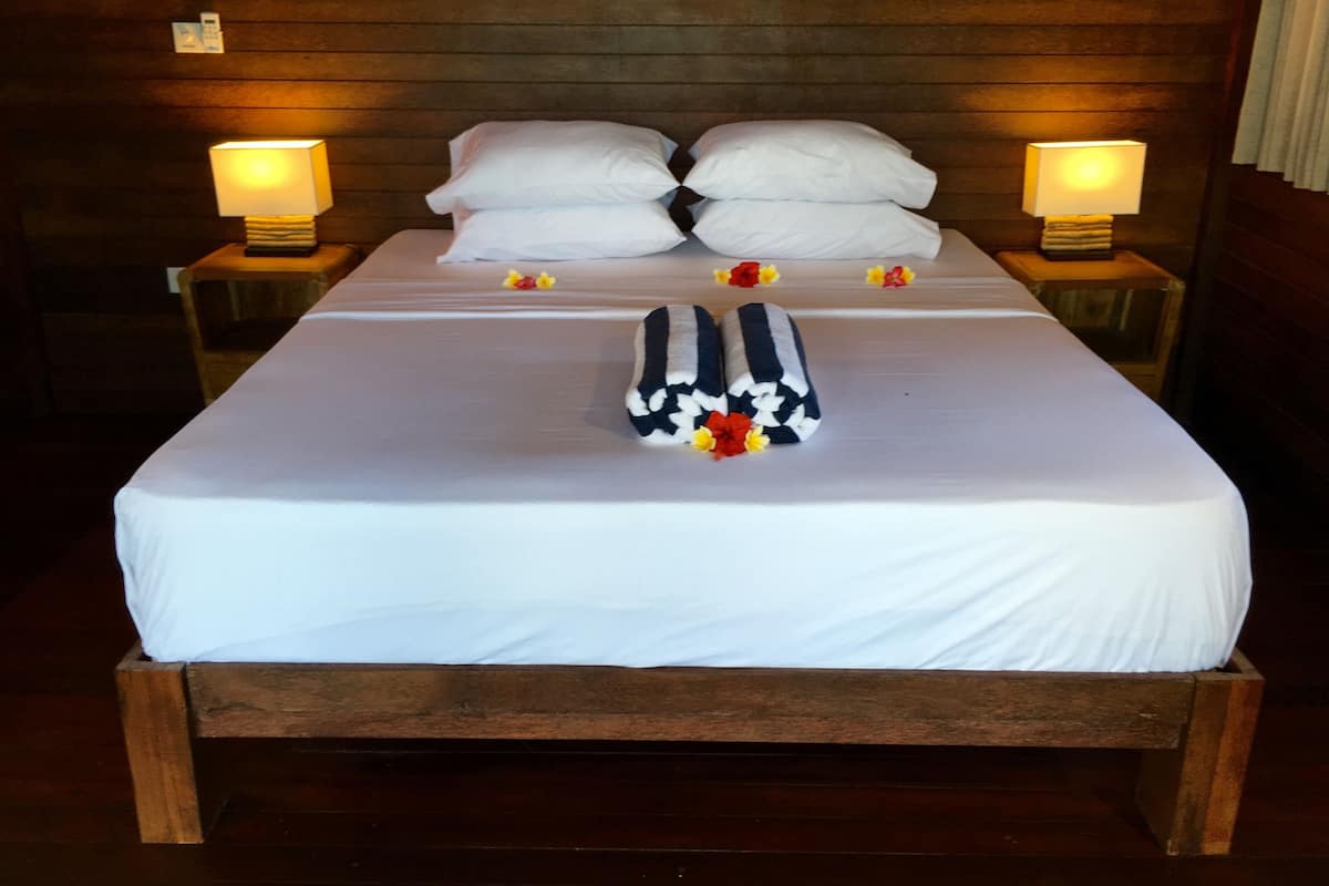 A neatly made bed with white linens, two bedside lamps, and a floral pillow.