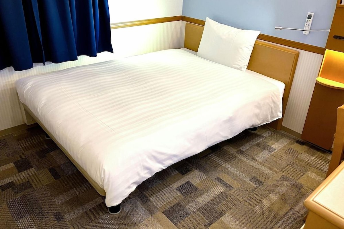 Une chambre d’hôtel avec un grand lit, une table de chevet, une lampe et un téléphone.