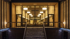 Entrada de hotel con una escalera que sube hacia un interior iluminado, rodeada de nieve.
