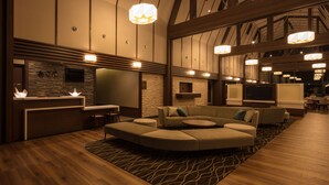 Un amplio vestíbulo de diseño moderno, con un sofá modular grande, un mostrador de recepción y una pantalla grande.