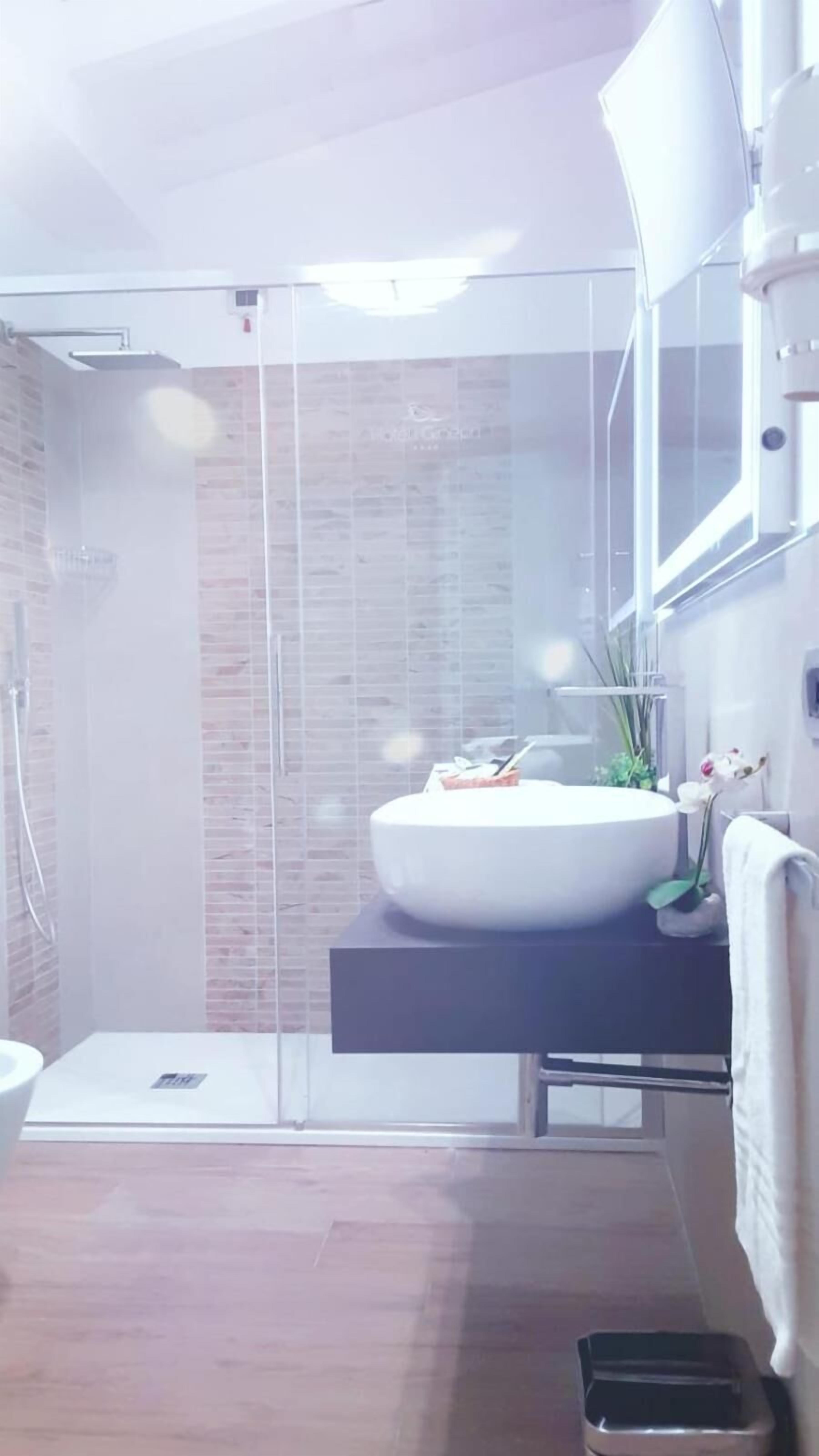 A modern bathroom with a glass shower enclosure, a white sink, and a mirror above it.