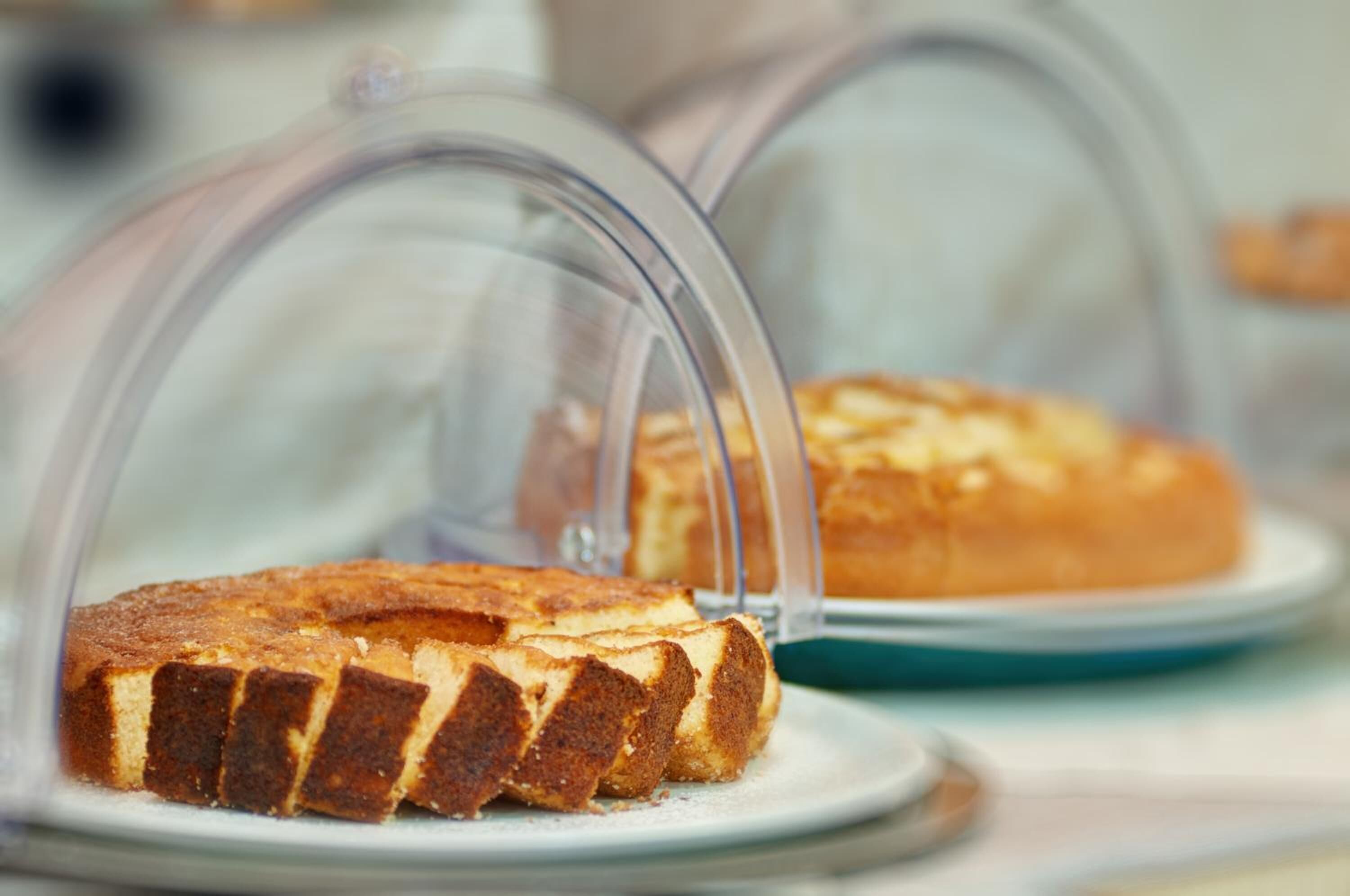 A display case with a cake and a pie under a glass dome.