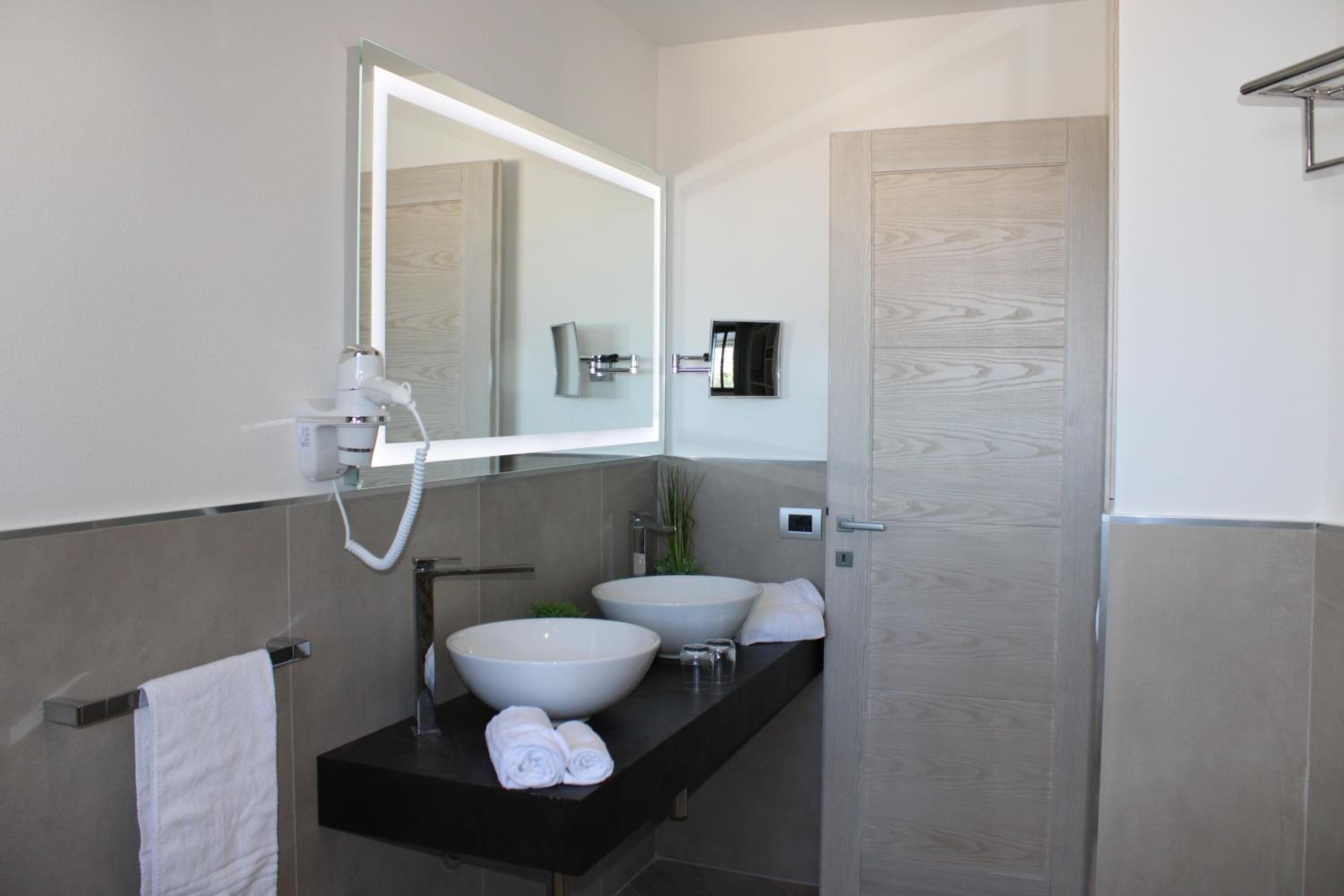 A modern bathroom with two large sinks, a mirror, and a towel rack.