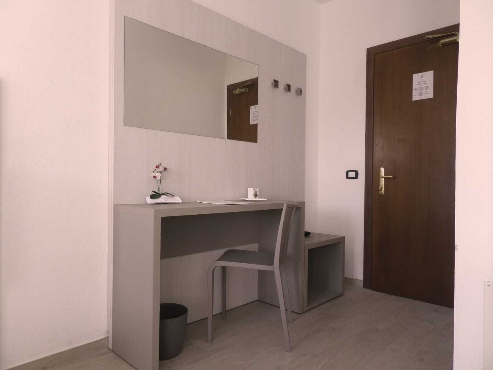 A small, modern bathroom with a grey vanity, a mirror, and a wooden door.