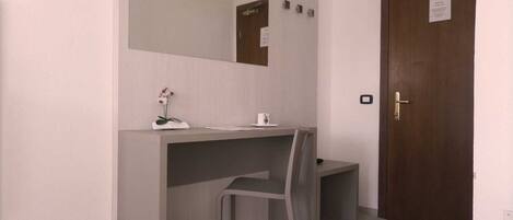 A small, modern bathroom with a grey vanity, a mirror, and a wooden door.