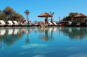 Zona de piscina amb gandules i ombrelles.