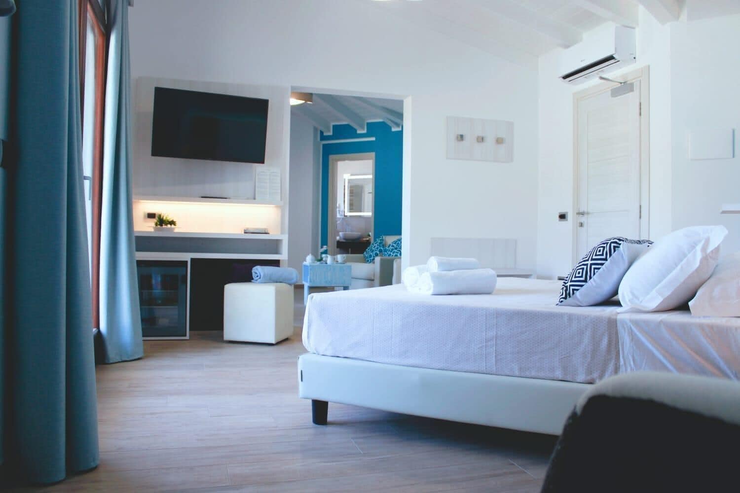 A modern hotel room with a bed, a desk, a TV, and a bathroom.