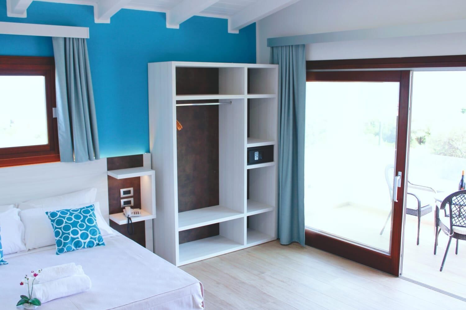 A hotel room with a bed, a wardrobe, a desk, and a balcony.