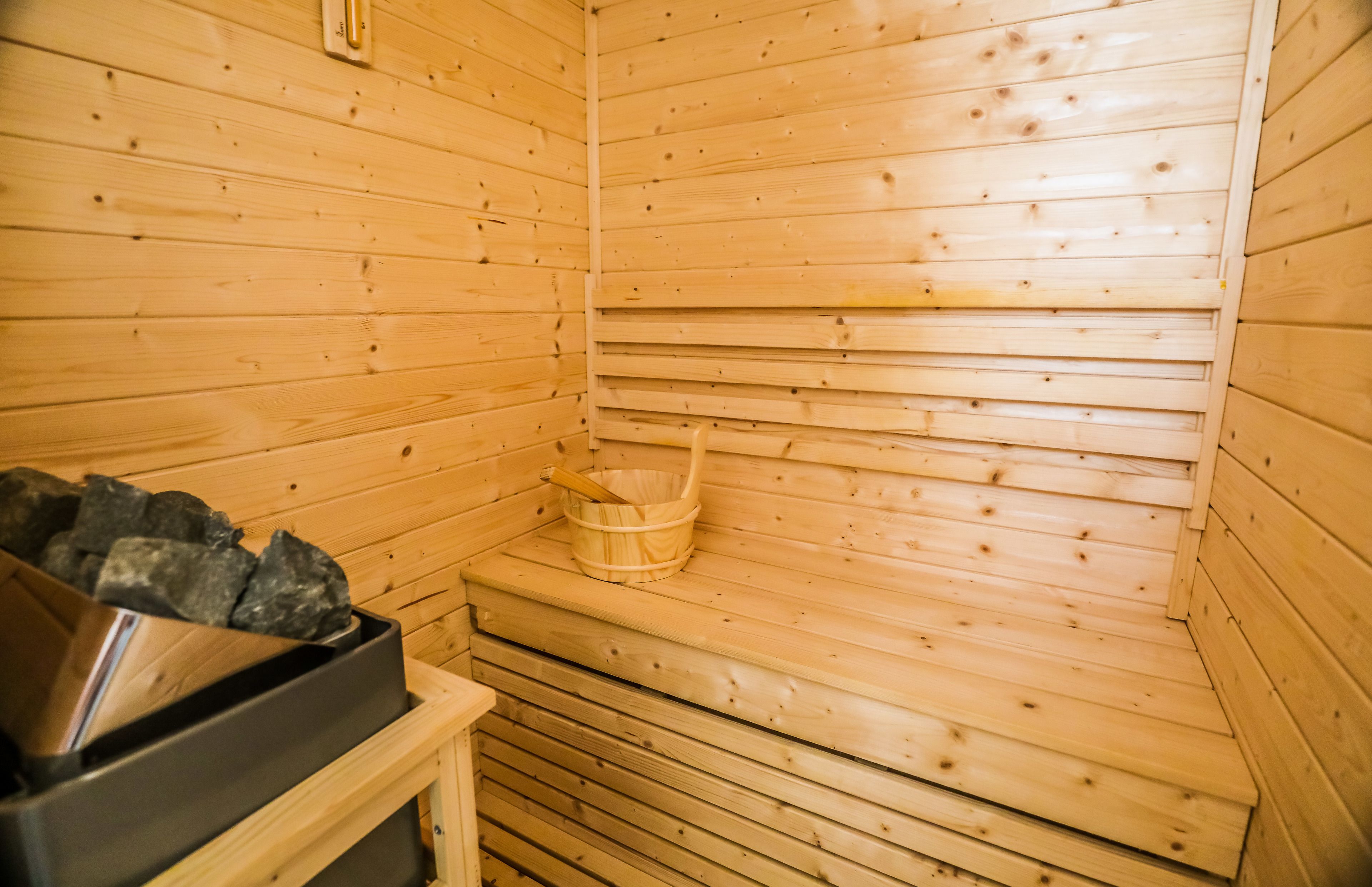 A wooden sauna with a stone basin and a wooden bucket.