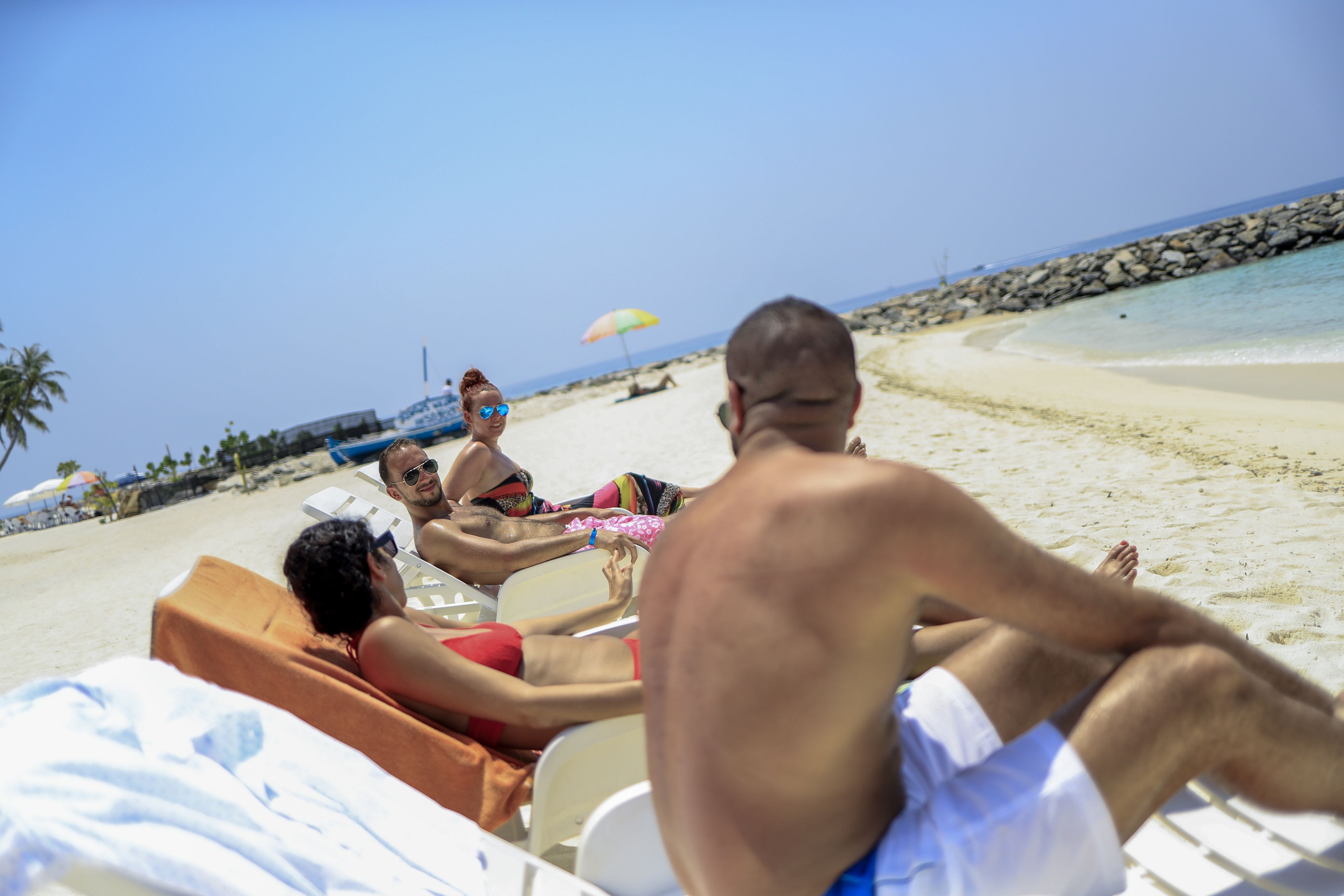 Escena de playa con gente descansando en tumbonas.