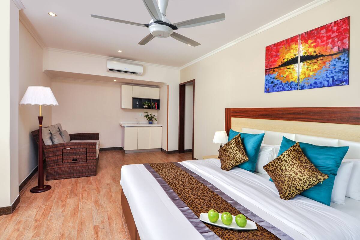 Quarto de hotel com cama, mesa de cabeceira, luminária e um quadro na parede.