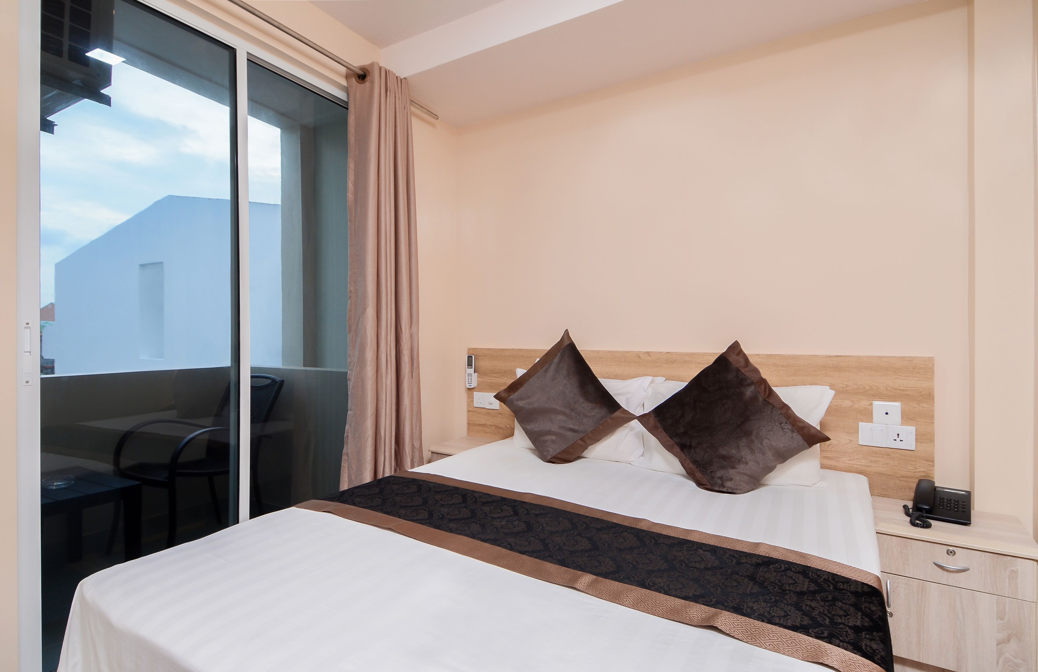 Una habitación de hotel con cama, mesita de noche y teléfono.