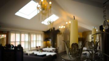 A dining area with a chandelier, candles, and a table set for a meal.