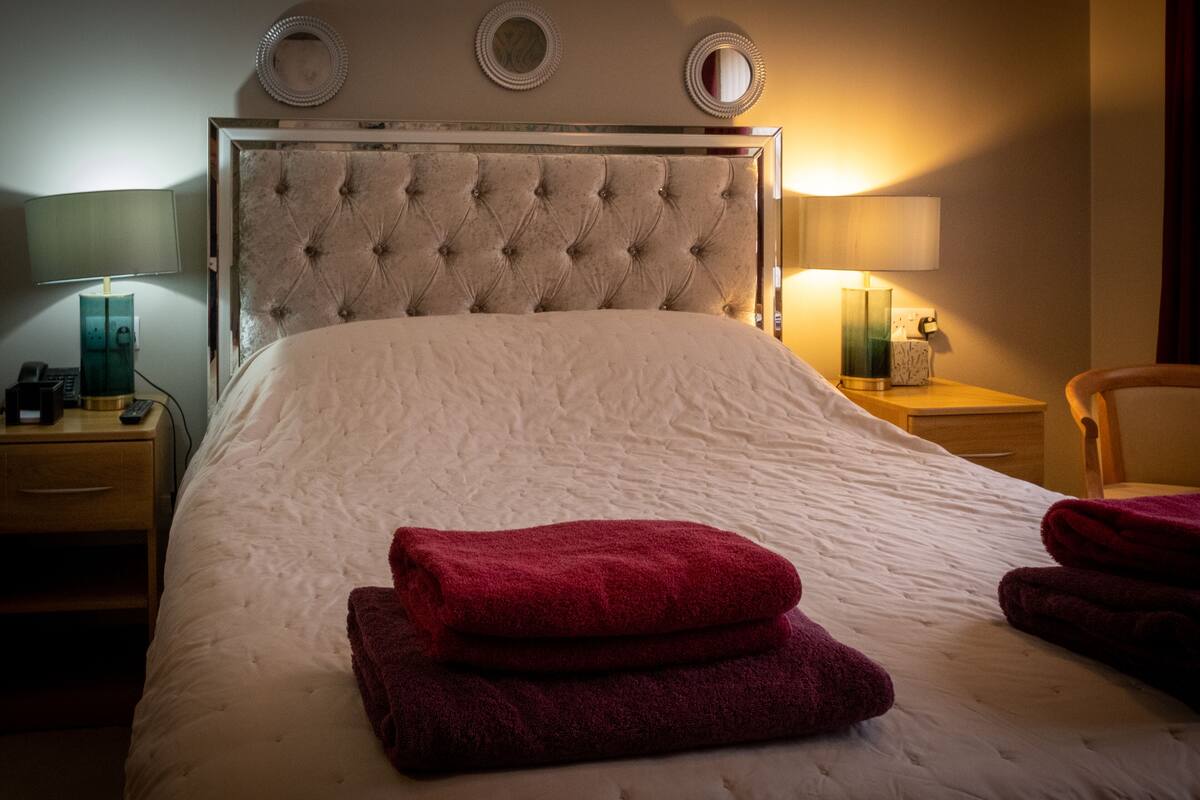 Een hotelkamer met een groot bed, twee nachtkastjes en drie wandlampen.