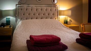 A hotel room with a large bed, two bedside tables, and three wall-mounted lamps.