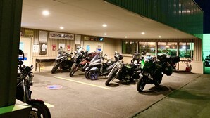 Un estacionamiento con varias motocicletas aparcadas frente a un edificio que muestra un cartel con indicaciones sobre la disponibilidad de espacios.