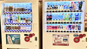Dos máquinas expendedoras con el rótulo 'Cans Shop' que ofrecen diversas bebidas y aperitivos.