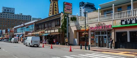 Vista de una calle con un hotel, tiendas y un paso de peatones.
