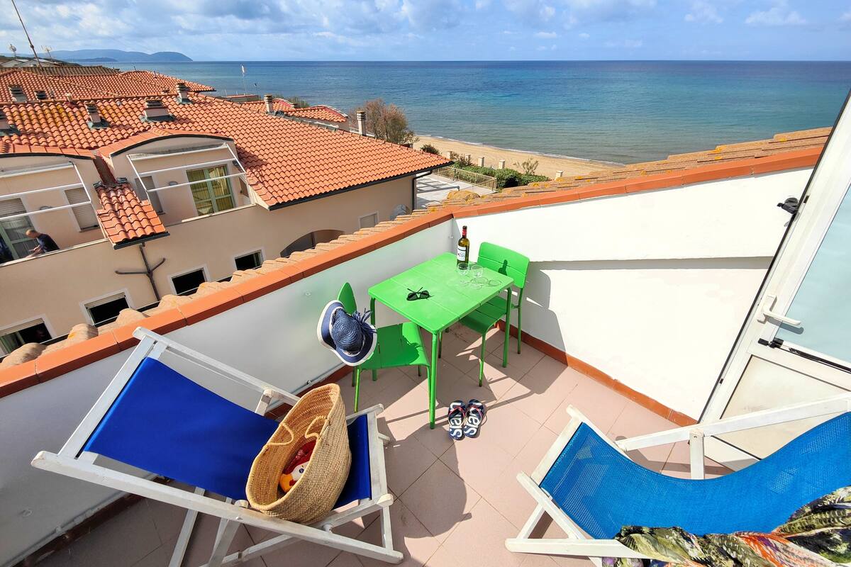 A balcony with a table, chairs, and a view of the sea.