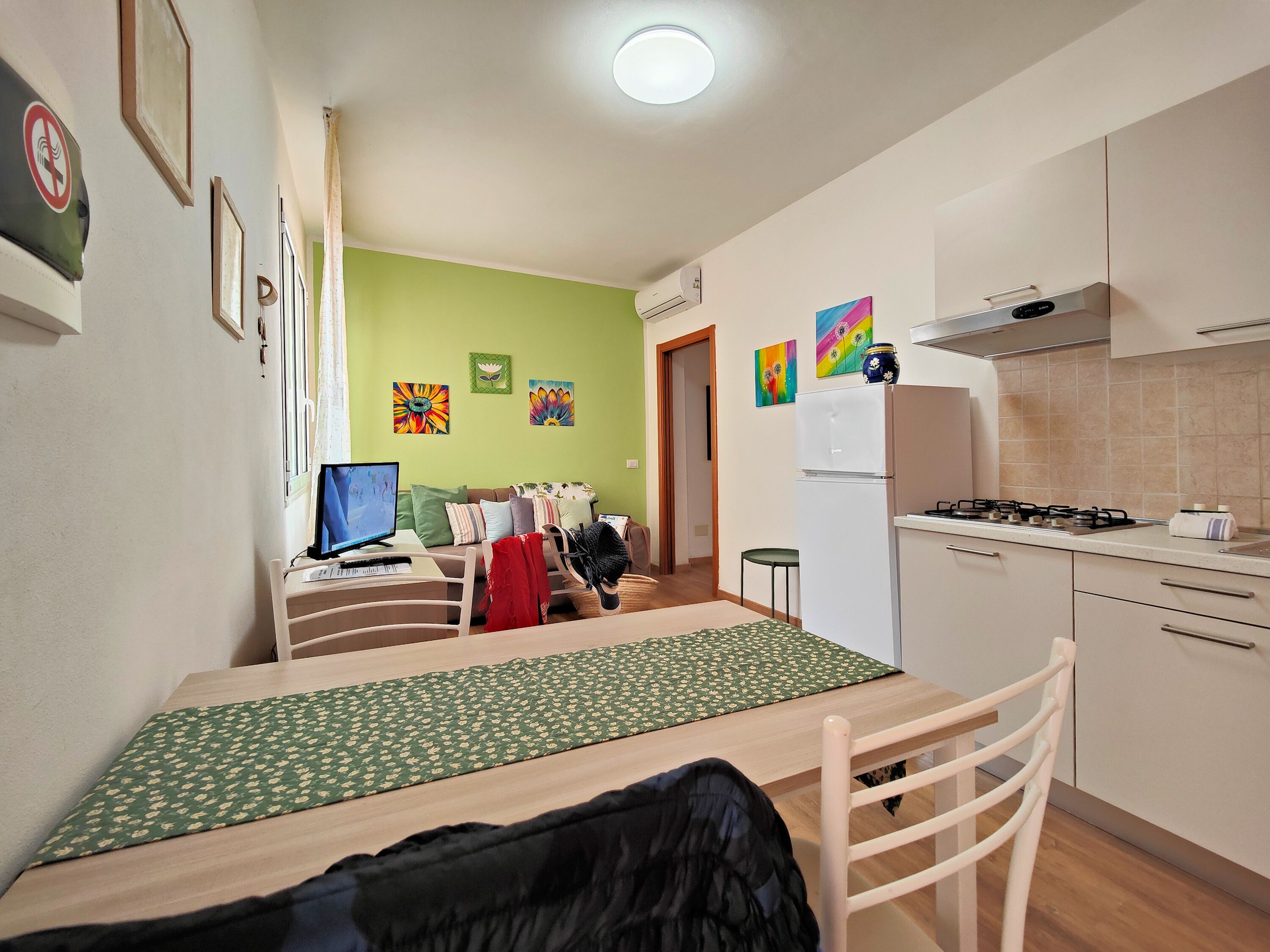 A compact kitchen with a dining area, a TV, and a refrigerator.