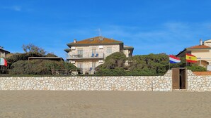 Ein zweistöckiges Steinhaus mit Balkon, umgeben von einer Steinmauer und Pflanzen.