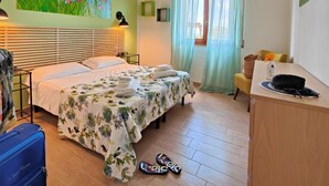 Ein Hotelzimmer mit Bett, Schreibtisch, Stuhl, Koffer und Hausschuhen.