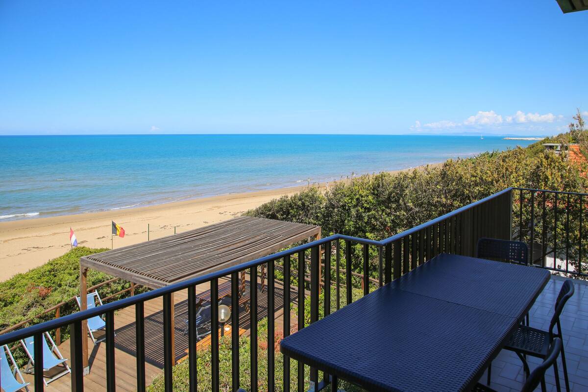 A balcony with a view of the beach and ocean.