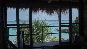 A room with a large window overlooking a turquoise sea, a thatched roof, and wooden flooring. - Castaway Resort Koh Lipe (Koh Lipe)