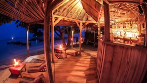 A wooden beach bar with a thatched roof, lounge chairs, and a bar area with bottles. - Castaway Resort Koh Lipe (Koh Lipe)